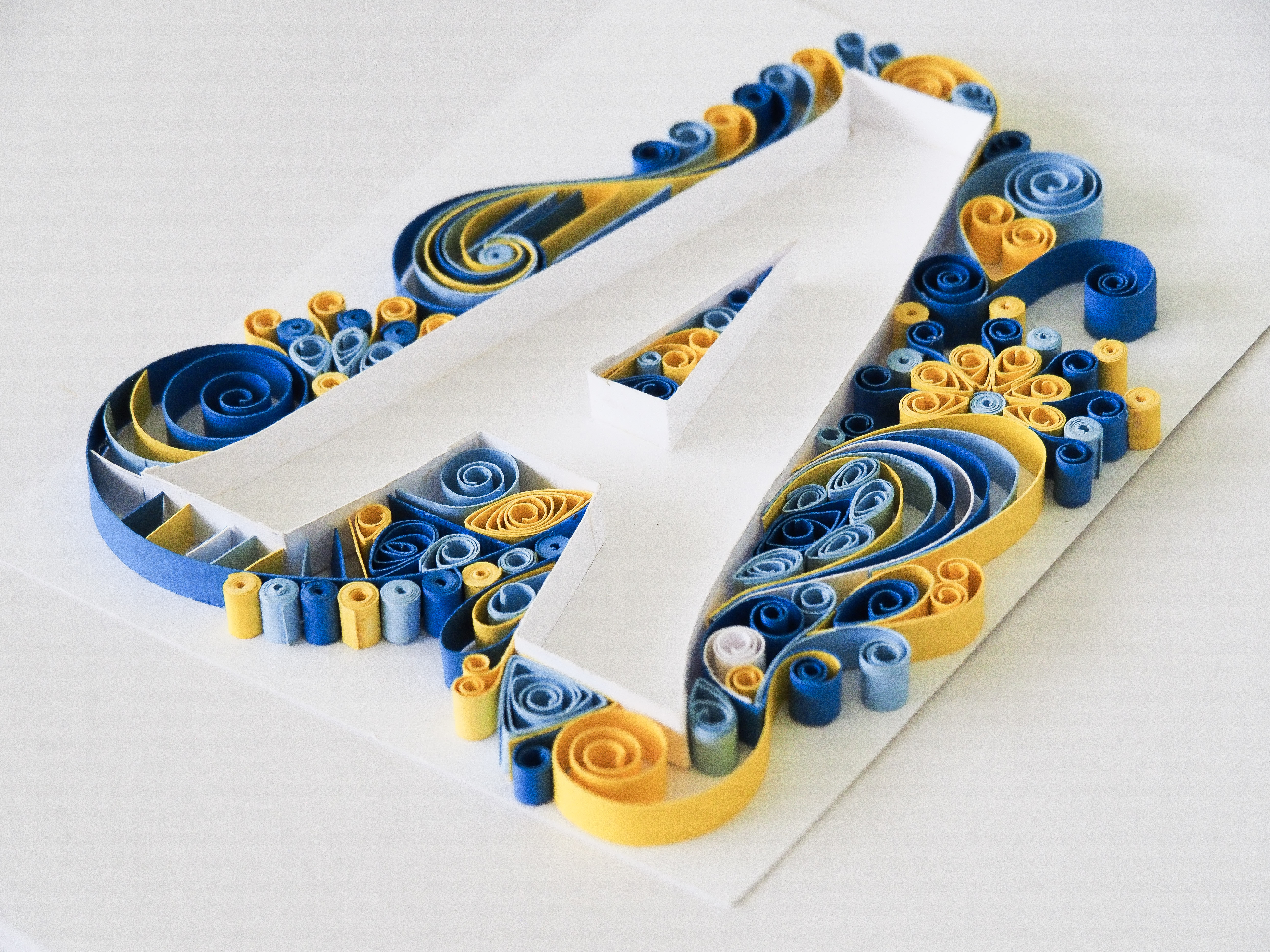 Close-up detail of blues and yellow paper quilling coils on Quilled Letter A