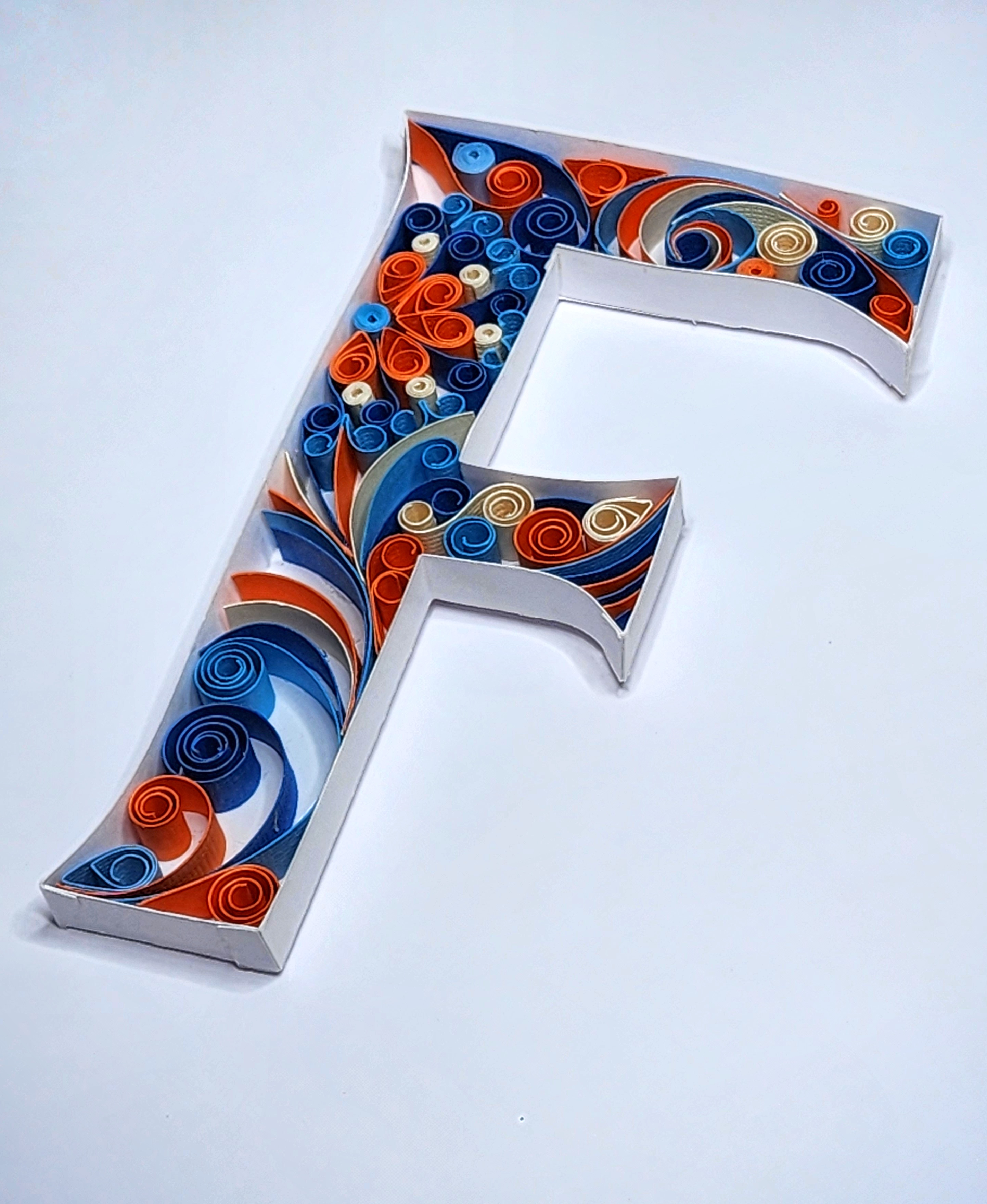 Close-up detail of blue and orange paper quilling coils on Quilled Letter F