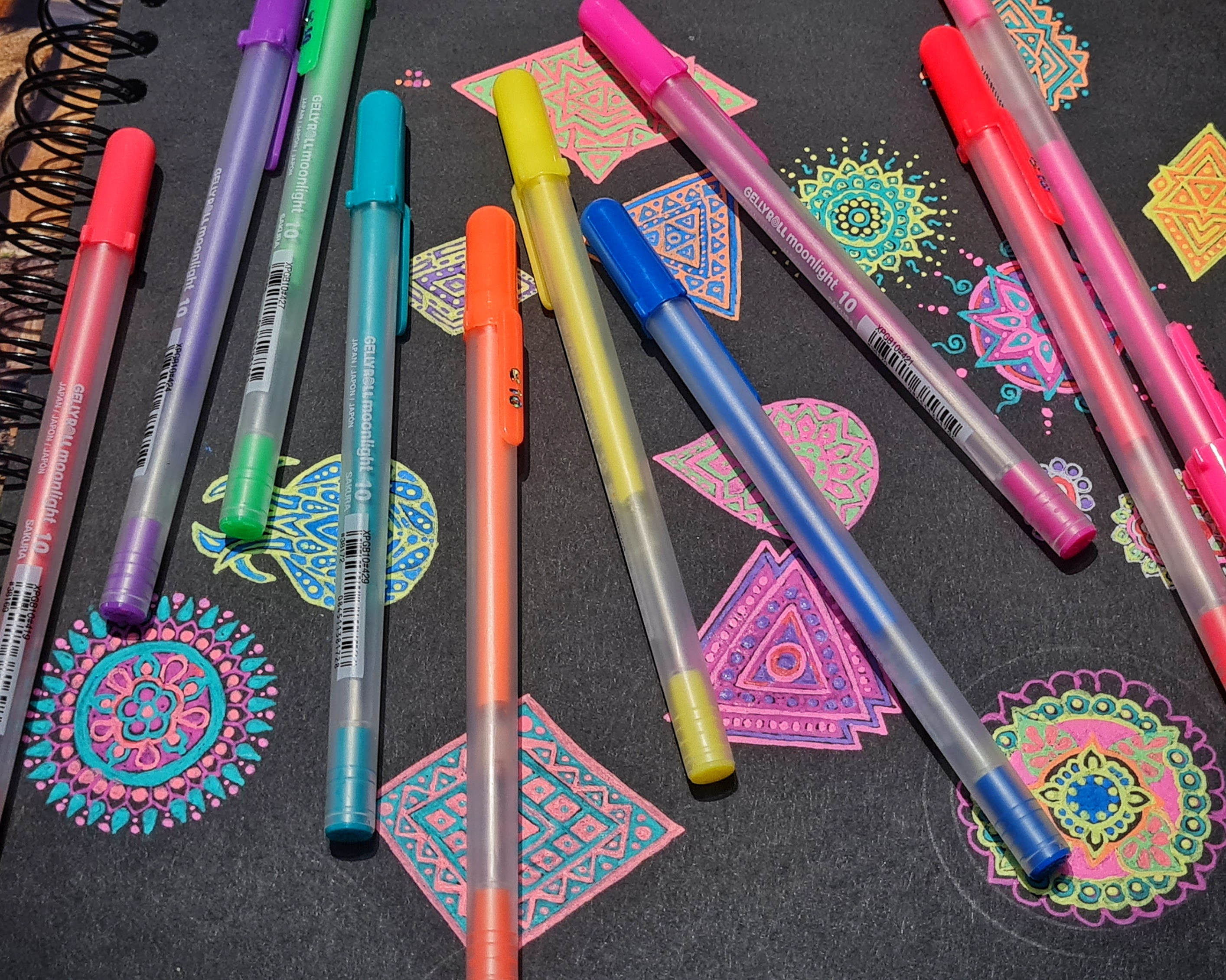 Colourful mandala doodles with neon pens scattered across black paper — Fractal Alley studio